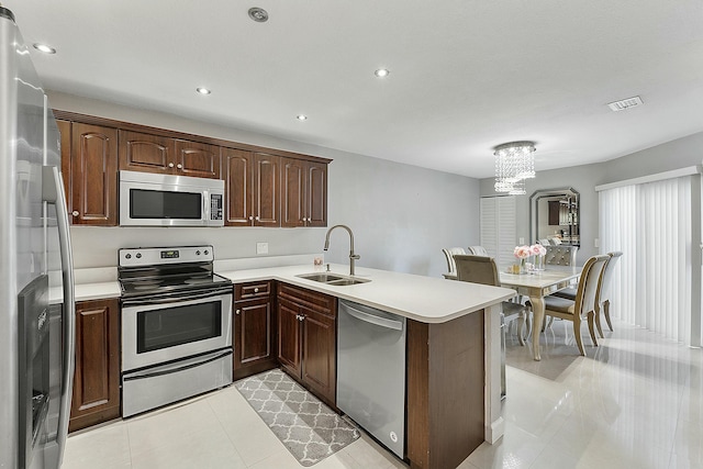 kitchen featuring sink, stainless steel appliances, a notable chandelier, kitchen peninsula, and light tile patterned flooring