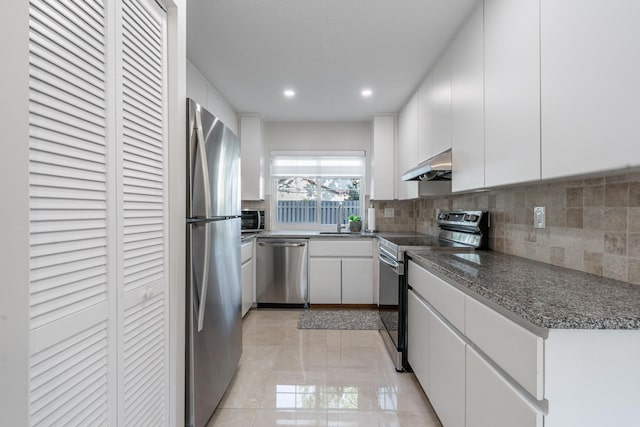 kitchen with light tile patterned flooring, white cabinetry, dark stone counters, decorative backsplash, and stainless steel appliances