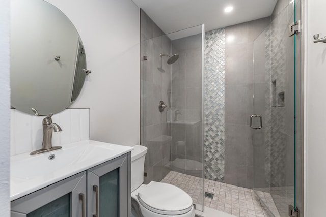 bathroom featuring vanity, a shower with shower door, and toilet