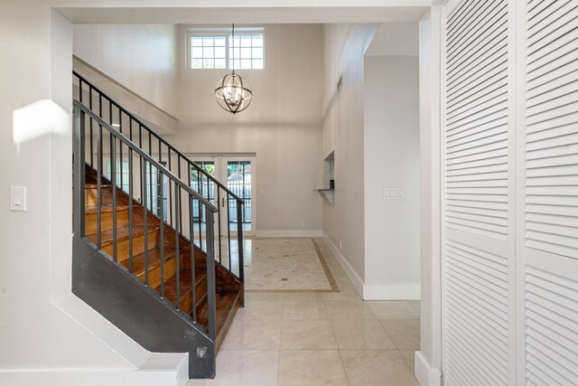 tiled entryway featuring a towering ceiling and a chandelier