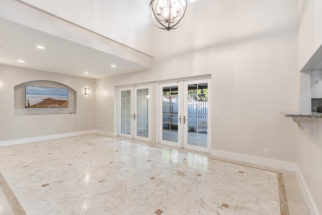 interior space with french doors, a towering ceiling, and an inviting chandelier