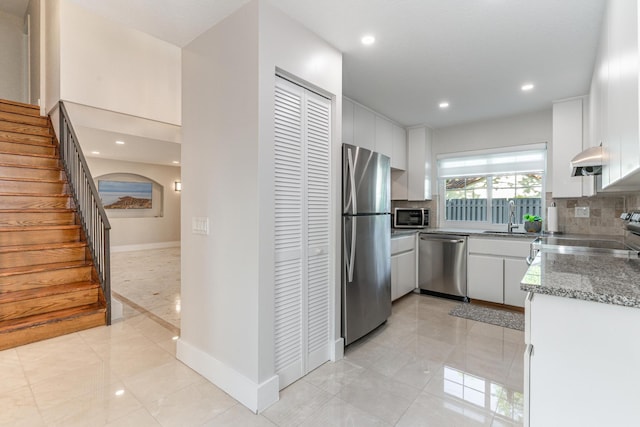 kitchen featuring sink, white cabinetry, tasteful backsplash, appliances with stainless steel finishes, and dark stone counters