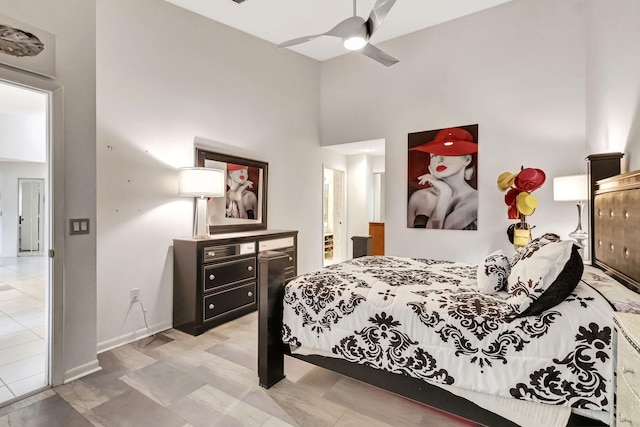 tiled bedroom with ceiling fan and a high ceiling