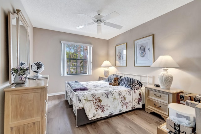 bedroom featuring ceiling fan, light hardwood / wood-style flooring, and a textured ceiling