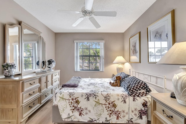 bedroom featuring a textured ceiling, light hardwood / wood-style flooring, and ceiling fan