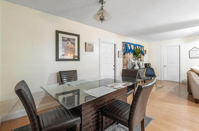 dining space featuring a textured ceiling and light wood-type flooring