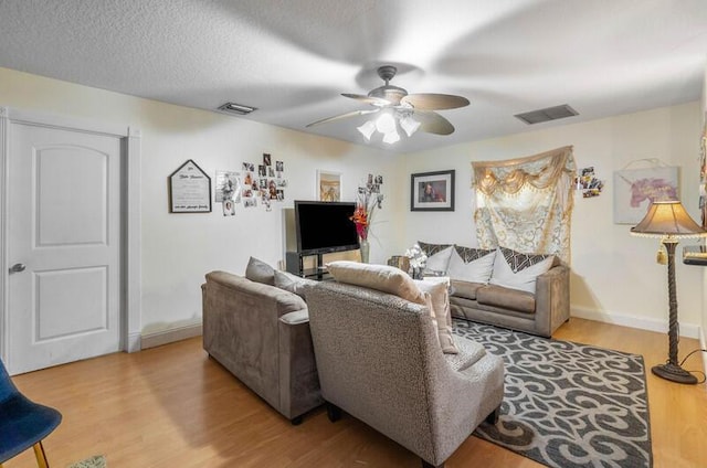 living room featuring a textured ceiling, light hardwood / wood-style flooring, and ceiling fan