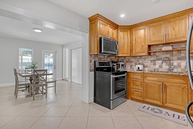 kitchen with light stone countertops, backsplash, stainless steel appliances, sink, and light tile patterned floors