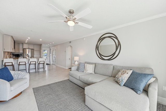 tiled living room with ceiling fan and crown molding