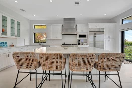 kitchen with wall chimney exhaust hood, stainless steel built in refrigerator, a breakfast bar area, and a center island