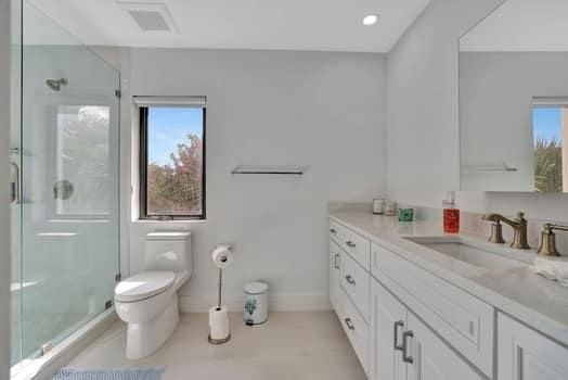 bathroom featuring tile patterned floors, toilet, vanity, and an enclosed shower