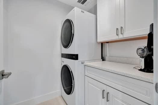 clothes washing area featuring cabinets and stacked washer and dryer