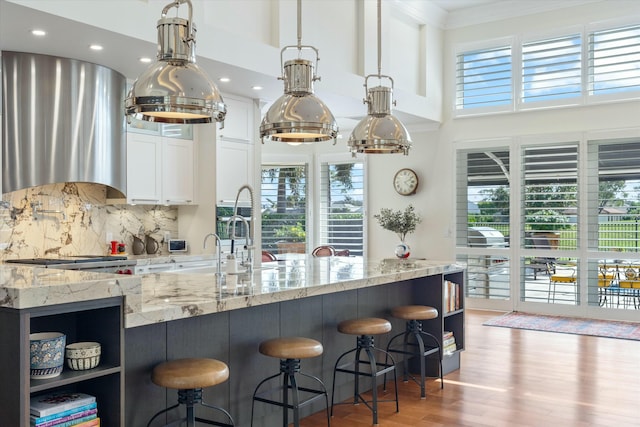 kitchen featuring light stone counters, exhaust hood, white cabinetry, backsplash, and open shelves