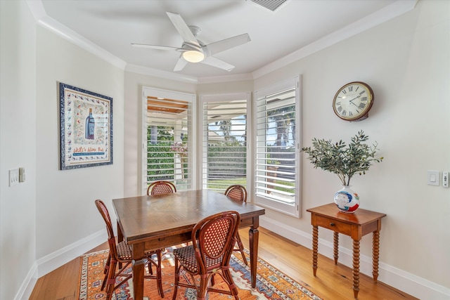 dining area featuring ornamental molding, light wood-style flooring, and baseboards