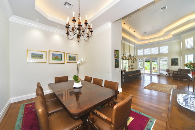 dining room featuring a tray ceiling, a notable chandelier, visible vents, dark wood-type flooring, and baseboards