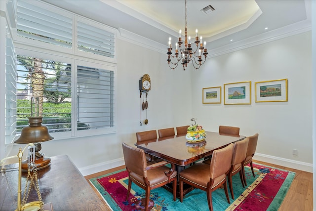 dining area featuring ornamental molding, wood finished floors, a raised ceiling, and baseboards