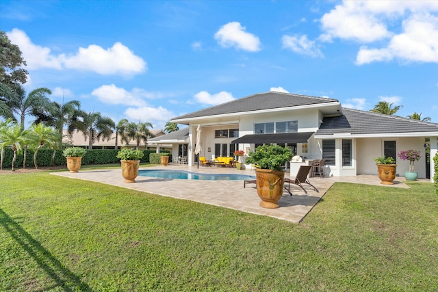 back of property featuring a patio area, a lawn, a fenced in pool, and a tiled roof