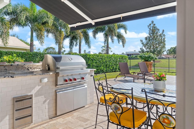 view of patio with a grill, fence, and an outdoor kitchen