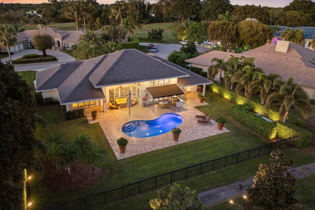 pool at dusk with a fenced in pool, a patio, a fenced backyard, a yard, and an outdoor living space