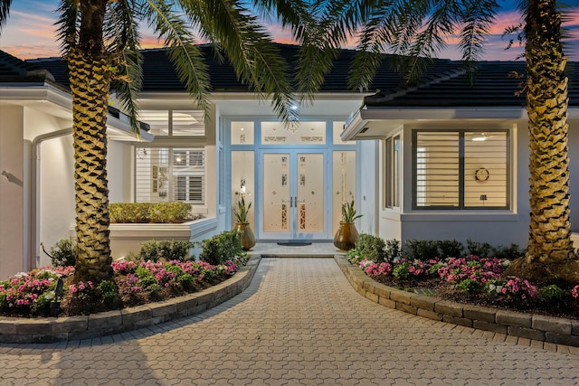 view of exterior entry featuring french doors and stucco siding