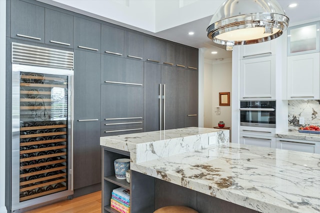 kitchen featuring beverage cooler, stainless steel oven, white cabinets, open shelves, and glass insert cabinets