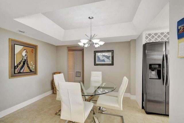 tiled dining room featuring a notable chandelier and a raised ceiling