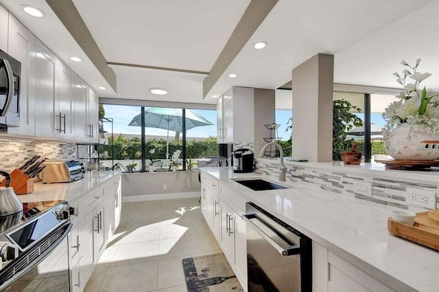 kitchen with white cabinetry, sink, stainless steel appliances, decorative backsplash, and light tile patterned floors