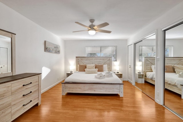 bedroom featuring ceiling fan, light hardwood / wood-style floors, and two closets