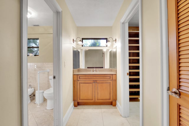 bathroom featuring vanity, a bidet, tile walls, tile patterned flooring, and toilet