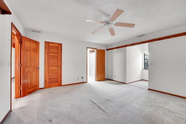 interior space featuring a textured ceiling, light colored carpet, and ceiling fan