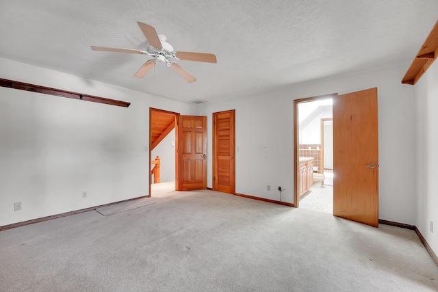 empty room featuring ceiling fan, light colored carpet, and a textured ceiling