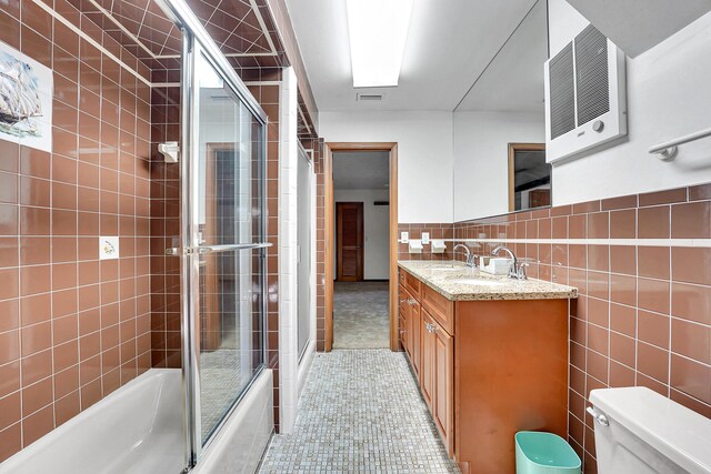 full bathroom featuring vanity, tile patterned floors, combined bath / shower with glass door, toilet, and tile walls