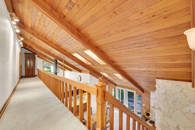 hallway with lofted ceiling with skylight, wooden walls, carpet, and wood ceiling