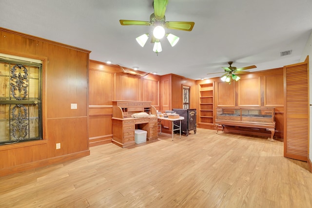 kitchen with a kitchen bar, light wood-type flooring, built in features, and ceiling fan