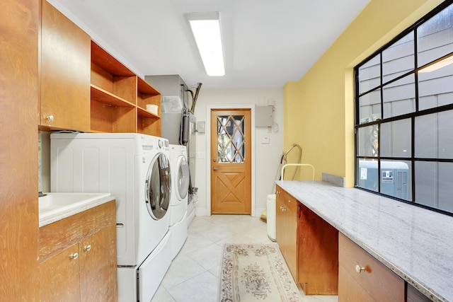 washroom with light tile patterned flooring, cabinets, separate washer and dryer, and a wealth of natural light