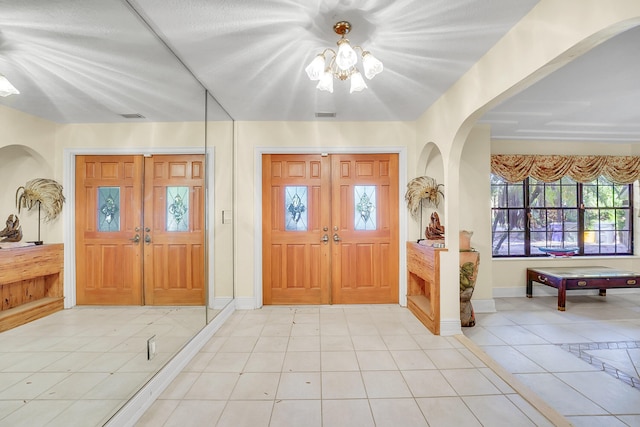 entryway featuring french doors, a notable chandelier, and light tile patterned flooring