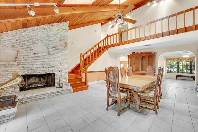 dining area featuring a skylight, ceiling fan, beam ceiling, wooden ceiling, and light tile patterned flooring