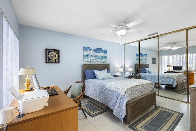 tiled bedroom with ceiling fan, a textured ceiling, and a closet