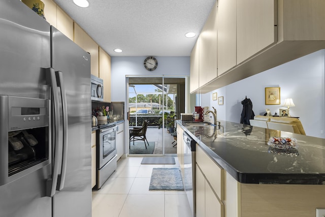 kitchen featuring dark stone counters, a textured ceiling, stainless steel appliances, sink, and light tile patterned floors