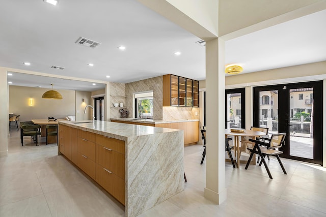 kitchen with sink, french doors, hanging light fixtures, a spacious island, and decorative backsplash