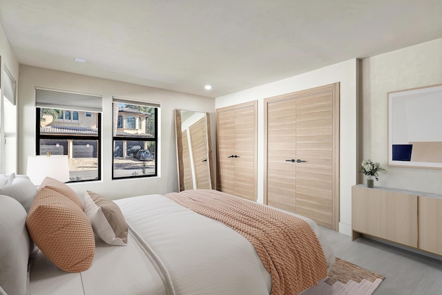 bedroom featuring light wood-type flooring and multiple closets