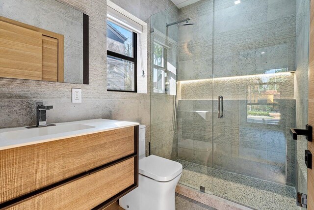 bathroom featuring tile patterned floors, toilet, bath / shower combo with glass door, and tile walls