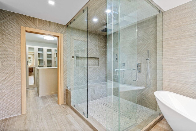 bathroom featuring shower with separate bathtub and tile walls