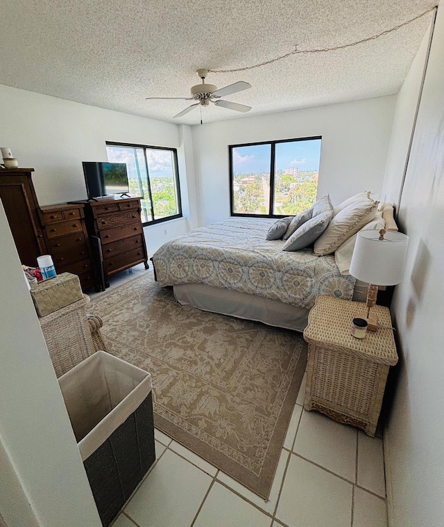 bedroom featuring ceiling fan, light tile patterned flooring, and a textured ceiling