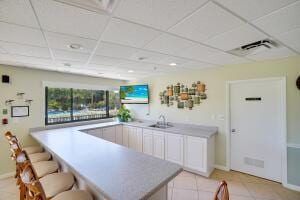 interior space with a paneled ceiling, white cabinetry, sink, and light tile patterned floors