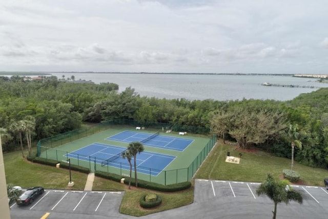 view of tennis court featuring a water view and a lawn