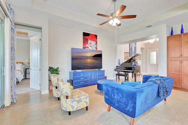 tiled living room featuring a tray ceiling and ceiling fan