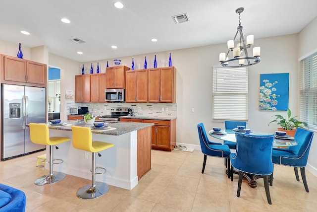 kitchen featuring a breakfast bar, a center island, hanging light fixtures, stainless steel appliances, and a chandelier