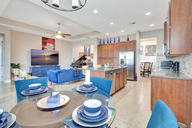 dining room featuring a raised ceiling, ceiling fan, sink, and light tile patterned floors