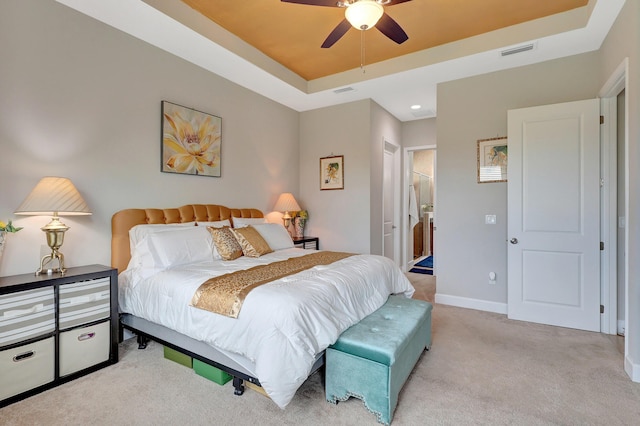 carpeted bedroom featuring ensuite bath, a raised ceiling, and ceiling fan